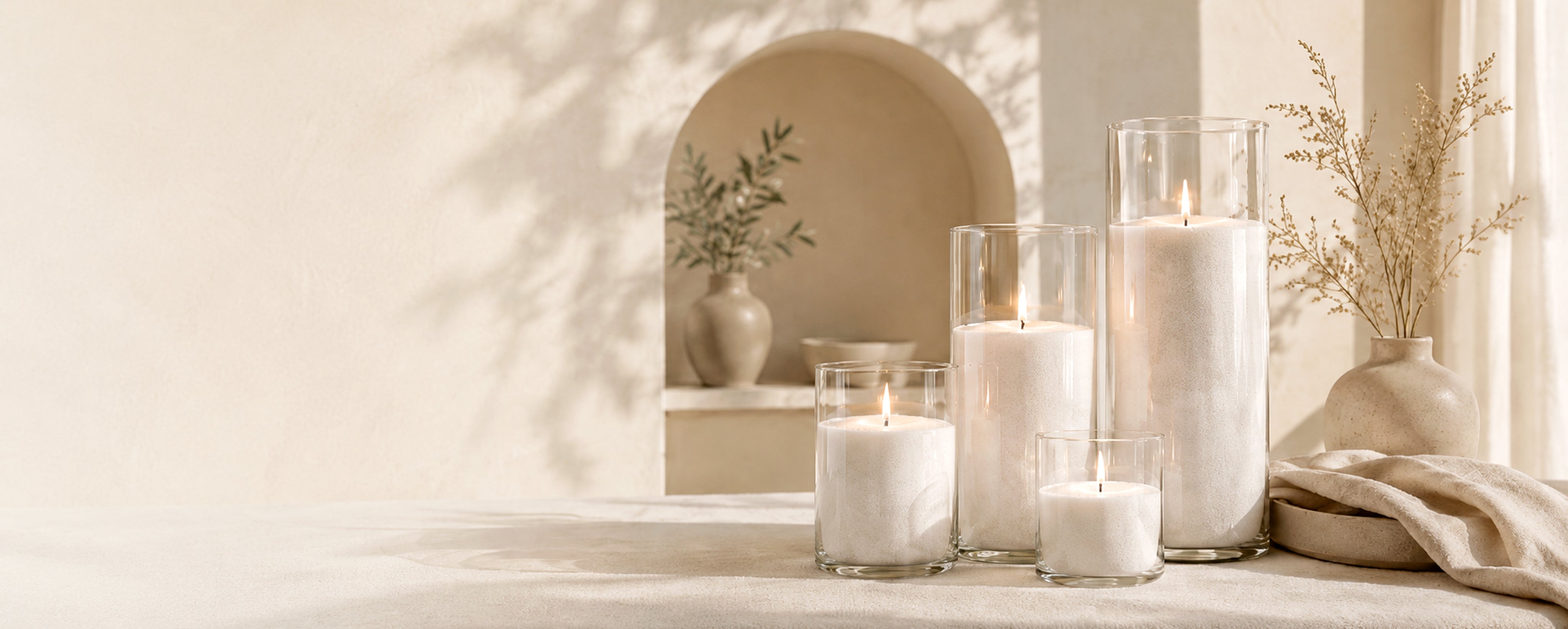 Candlelit scene with white candles in glass holders on a neutral background